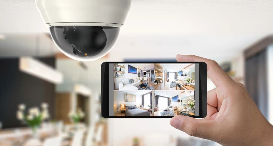 Homeowner holding smartphone with video feed from security cameras in Scottsdale